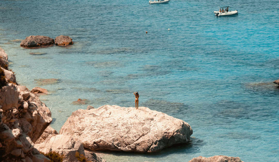 Woman standing on a rock taking a photo | The Italian On Tour