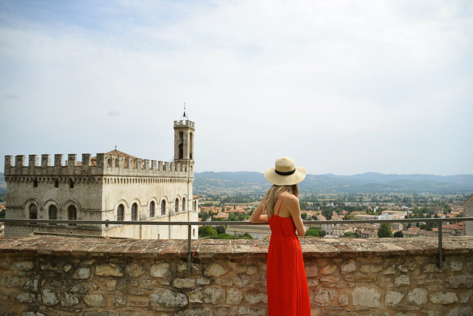 lady wearing red dress overlooking the city of gubbio italy | The Italian On Tour