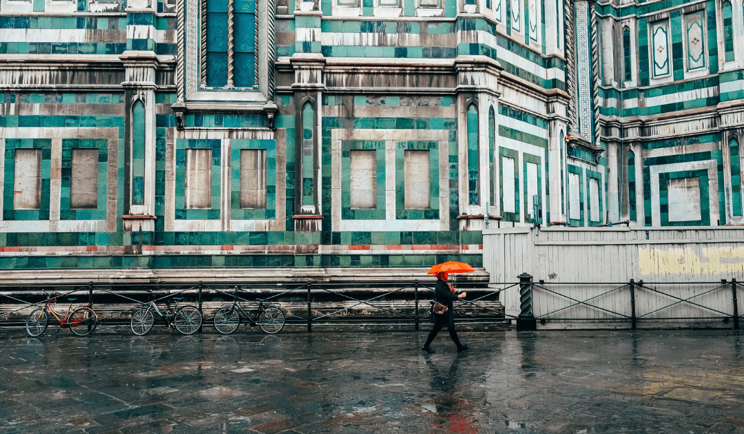 Man walking with orange umbrella in Florence in the rain | The Italian On Tour