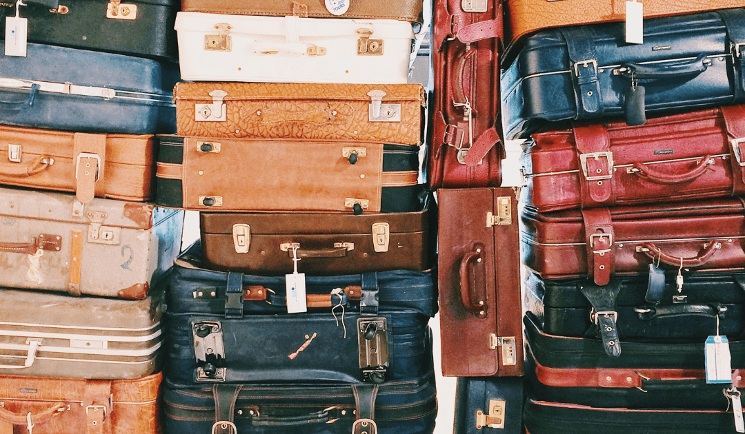 Assorted colored suitcases stacked in rows | The Italian On Tour